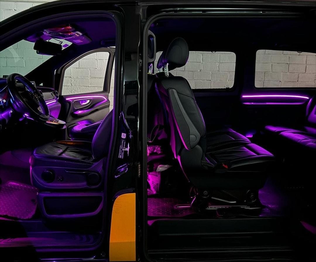 Shows a mercedes van front and back seats with pink LED lights